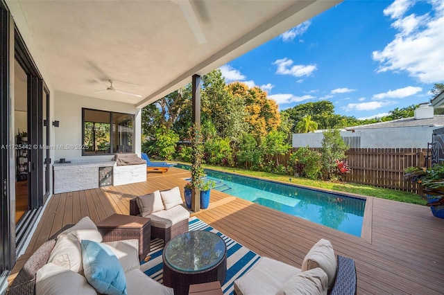 view of swimming pool featuring ceiling fan, an outdoor kitchen, outdoor lounge area, and a wooden deck