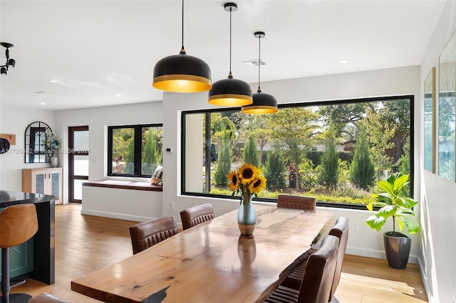 dining space with light wood-type flooring, a wealth of natural light, and french doors