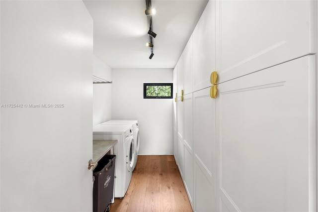 laundry room with light wood-type flooring, washer and dryer, and rail lighting