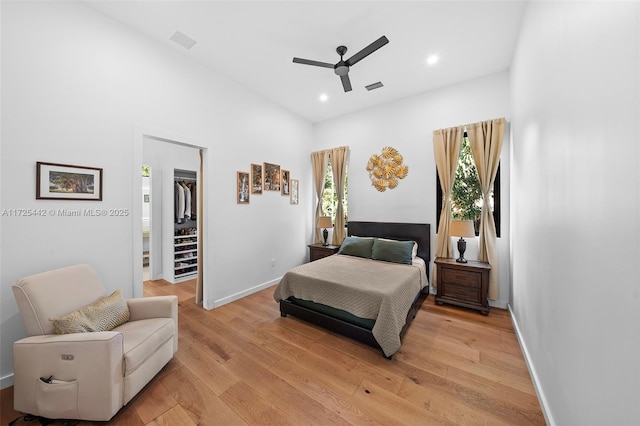 bedroom featuring light hardwood / wood-style floors, ceiling fan, a closet, a towering ceiling, and a walk in closet