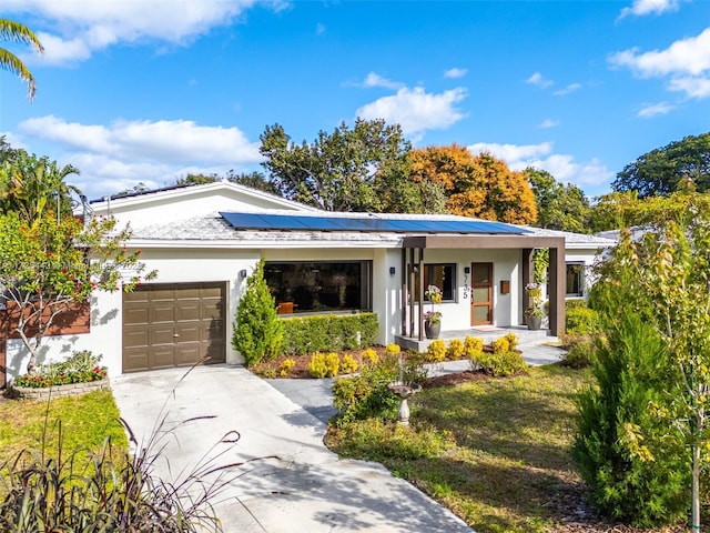 ranch-style house featuring a garage, solar panels, and a porch