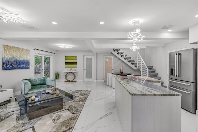 kitchen with an inviting chandelier, high end fridge, french doors, hanging light fixtures, and stone counters