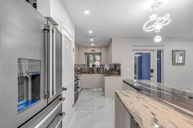 kitchen featuring decorative light fixtures, high quality fridge, dark stone countertops, a chandelier, and sink