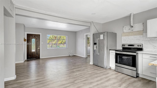 kitchen with appliances with stainless steel finishes, light hardwood / wood-style flooring, white cabinetry, and tasteful backsplash