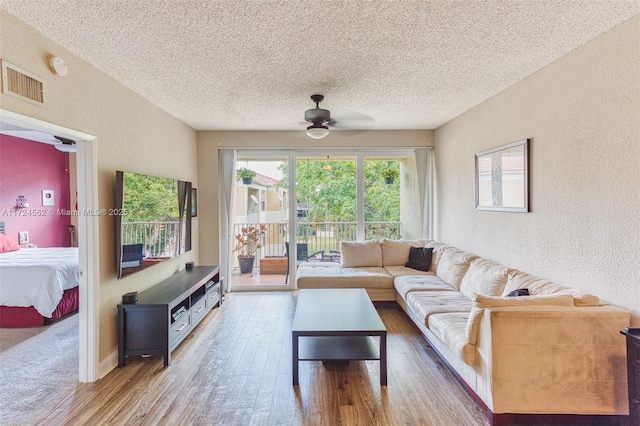 living room featuring ceiling fan, a textured ceiling, and hardwood / wood-style flooring