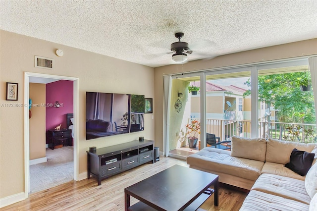 living room with a textured ceiling, ceiling fan, and light hardwood / wood-style floors