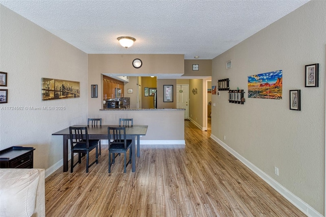 dining room featuring a textured ceiling and light hardwood / wood-style floors