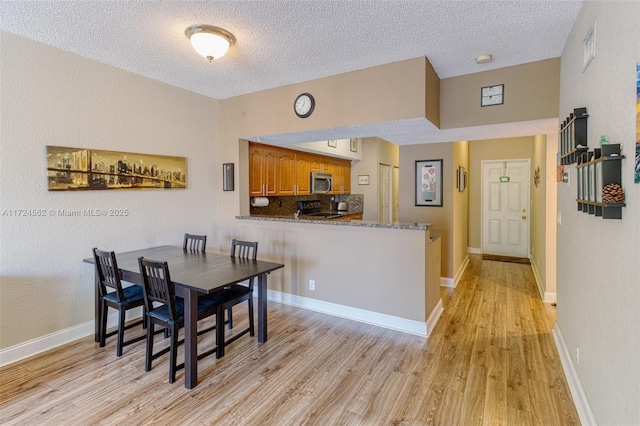 dining room with light wood-type flooring and a textured ceiling