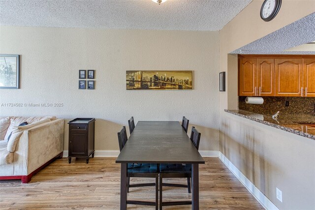 dining room featuring a textured ceiling and light hardwood / wood-style floors