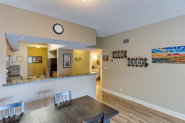 dining space with a textured ceiling and light hardwood / wood-style floors