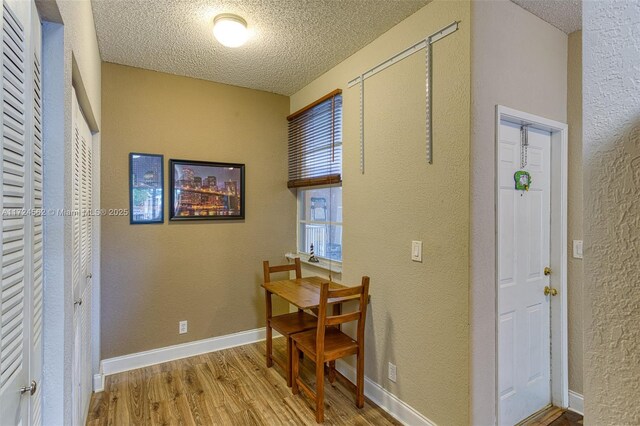 hall with a textured ceiling and light hardwood / wood-style floors