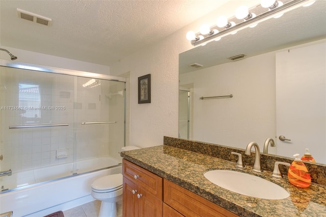 full bathroom with toilet, vanity, tile patterned floors, combined bath / shower with glass door, and a textured ceiling