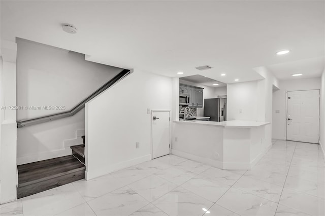 kitchen with appliances with stainless steel finishes, gray cabinetry, and kitchen peninsula