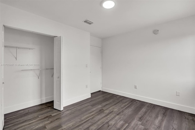 unfurnished bedroom with a closet and dark wood-type flooring