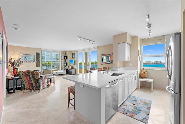 kitchen with kitchen peninsula, stainless steel appliances, a kitchen breakfast bar, white cabinets, and sink