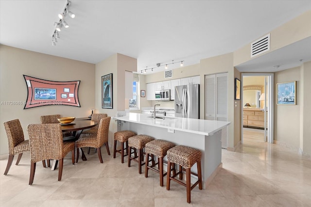 kitchen featuring kitchen peninsula, sink, white cabinetry, appliances with stainless steel finishes, and a breakfast bar area