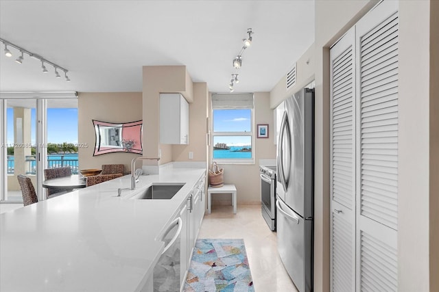 kitchen with a water view, white cabinets, sink, and stainless steel appliances