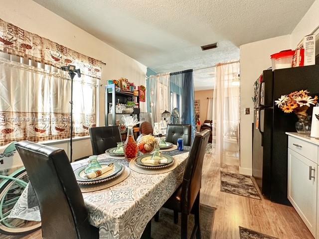 dining room with a textured ceiling and light hardwood / wood-style flooring