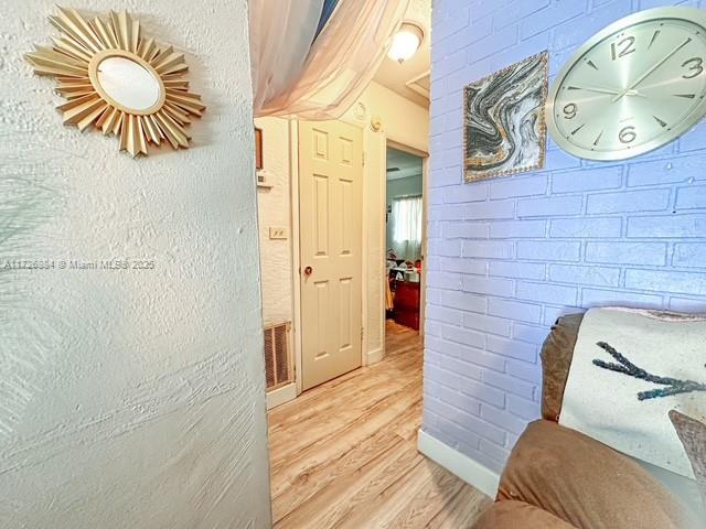 hallway with brick wall and light hardwood / wood-style floors