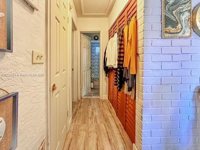 hall featuring brick wall and light hardwood / wood-style floors