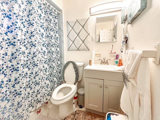 bathroom with toilet, vanity, and walk in shower