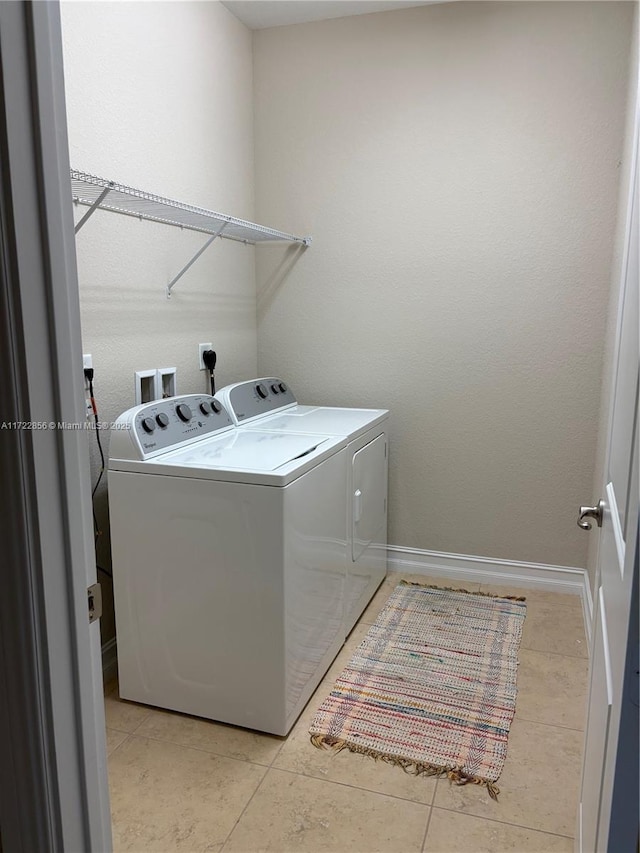 clothes washing area featuring light tile patterned floors and washer and clothes dryer