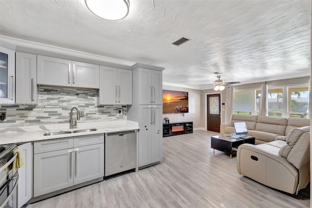 kitchen featuring ceiling fan, stainless steel appliances, backsplash, light wood-type flooring, and sink