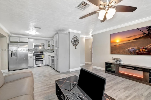 living room featuring light wood-type flooring, ceiling fan, ornamental molding, and a textured ceiling