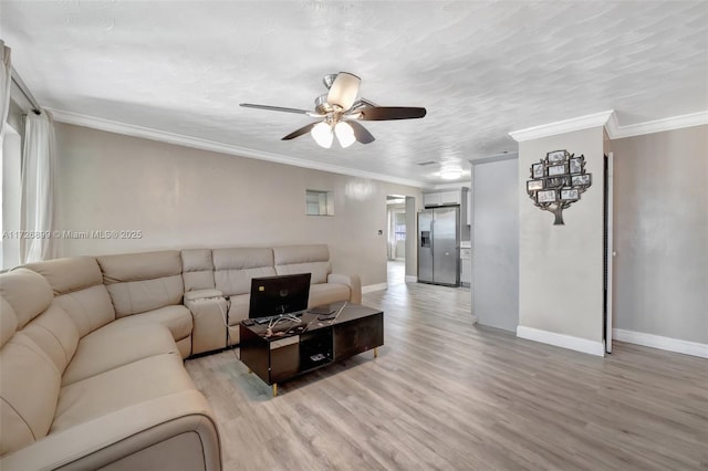 living room featuring ceiling fan, a textured ceiling, ornamental molding, and light wood-type flooring