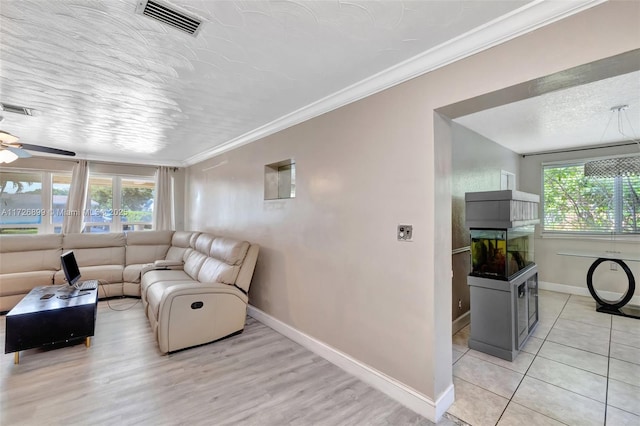 living room featuring ceiling fan, light tile patterned floors, crown molding, and a textured ceiling