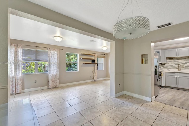 tiled spare room featuring a textured ceiling and sink