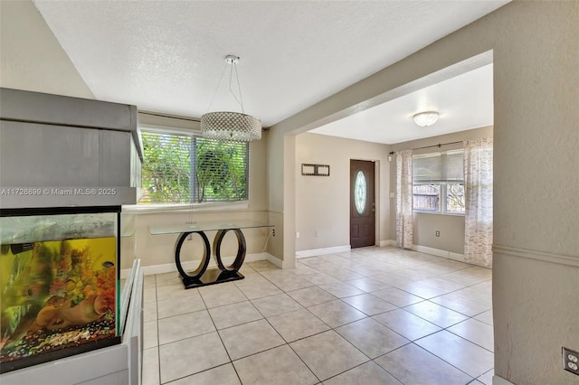 tiled foyer with a textured ceiling and a notable chandelier