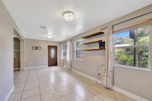 tiled entryway featuring a wealth of natural light and a notable chandelier