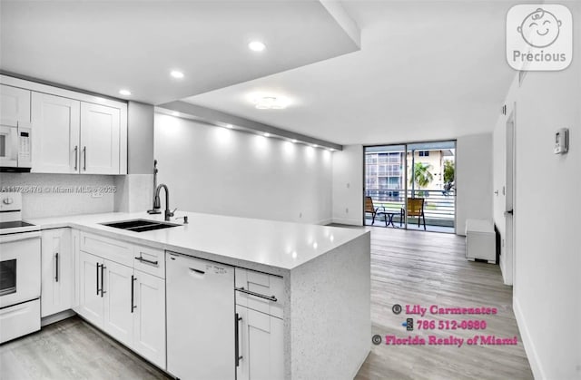 kitchen featuring white cabinetry, sink, white appliances, and kitchen peninsula