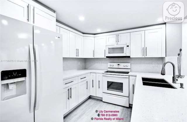 kitchen with tasteful backsplash, sink, white cabinets, white appliances, and light hardwood / wood-style flooring