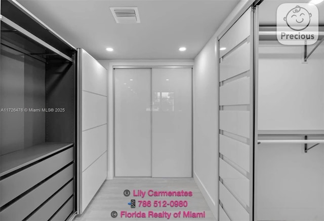 walk in closet with light hardwood / wood-style floors