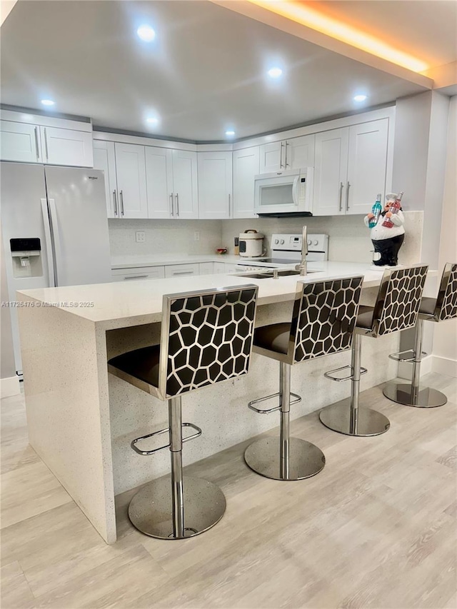 3725 NE 169th St Unit B-203, North Miami Beach, FL 33160 - kitchen featuring white appliances, light countertops, a kitchen bar, and a peninsula