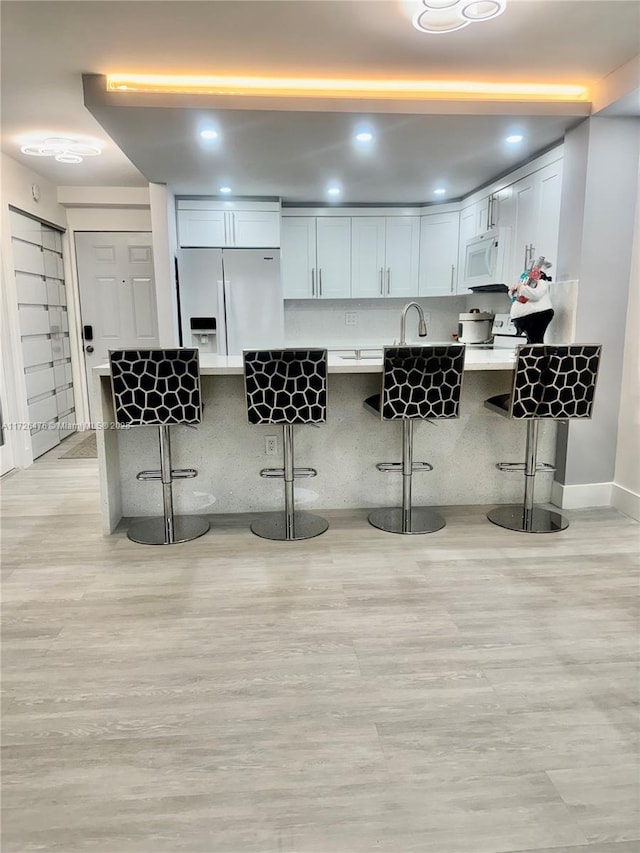 3725 NE 169th St Unit B-203, North Miami Beach, FL 33160 - kitchen featuring light countertops, a peninsula, white appliances, a sink, and a breakfast bar area