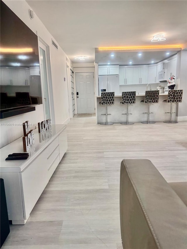 kitchen featuring a kitchen bar, white cabinets, and white appliances