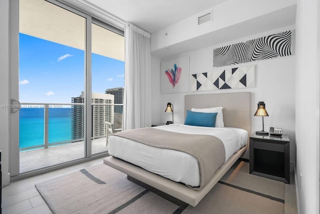 tiled bedroom with a water view, access to exterior, and floor to ceiling windows