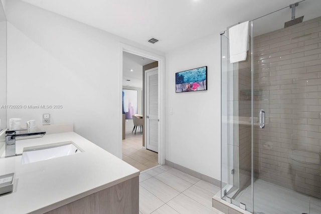 bathroom with tile patterned flooring, a shower with shower door, and vanity