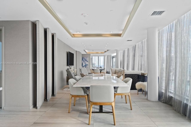 dining area with light tile patterned floors and a tray ceiling