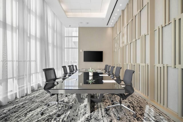 office area with expansive windows, a towering ceiling, and a tray ceiling