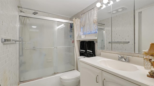 full bathroom with bath / shower combo with glass door, toilet, and vanity