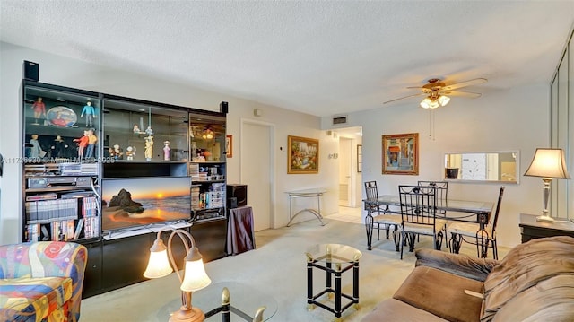 living room featuring ceiling fan, light colored carpet, and a textured ceiling