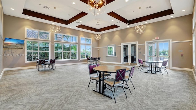 carpeted dining room with a raised ceiling, french doors, and a towering ceiling