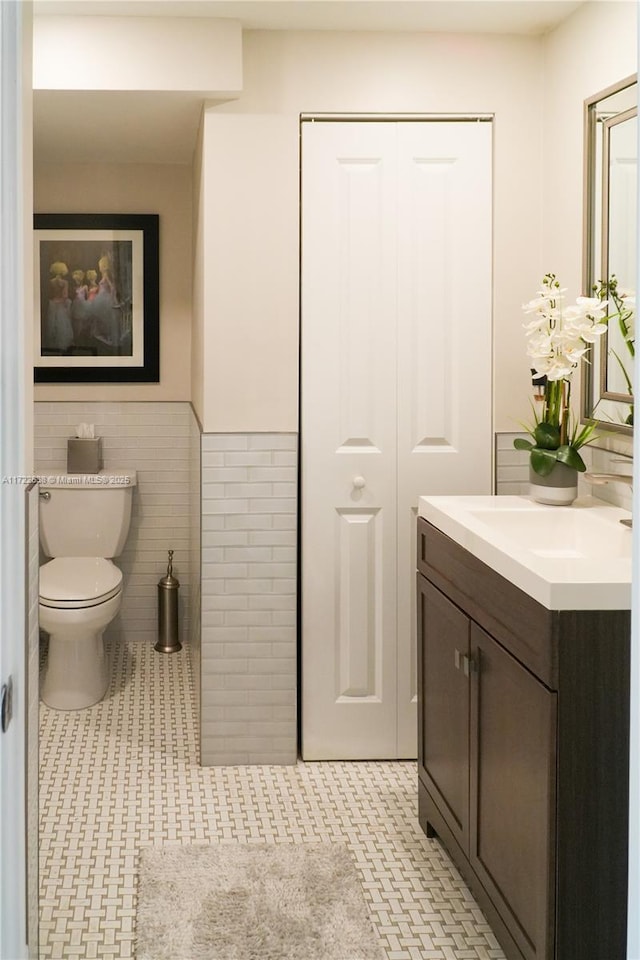 bathroom featuring tile walls, toilet, vanity, and tile patterned flooring