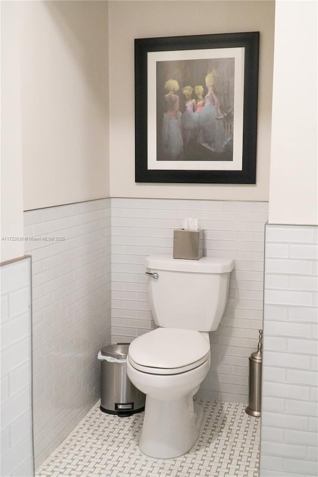 bathroom with toilet, tile patterned flooring, and tile walls