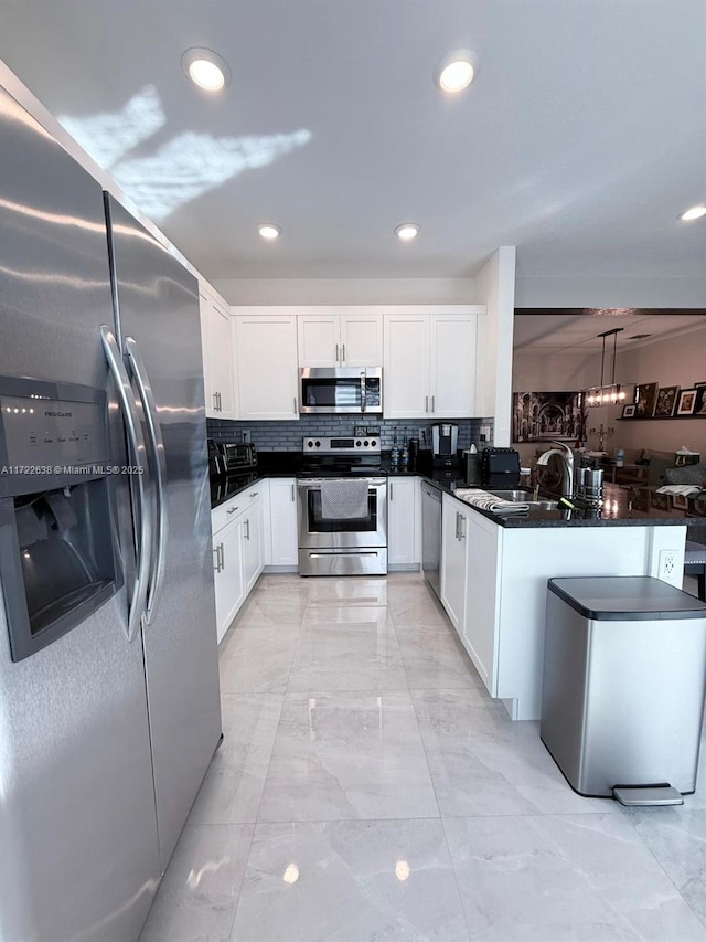 kitchen with stainless steel appliances, sink, white cabinetry, and decorative light fixtures