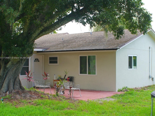 back of property with a lawn and a patio area